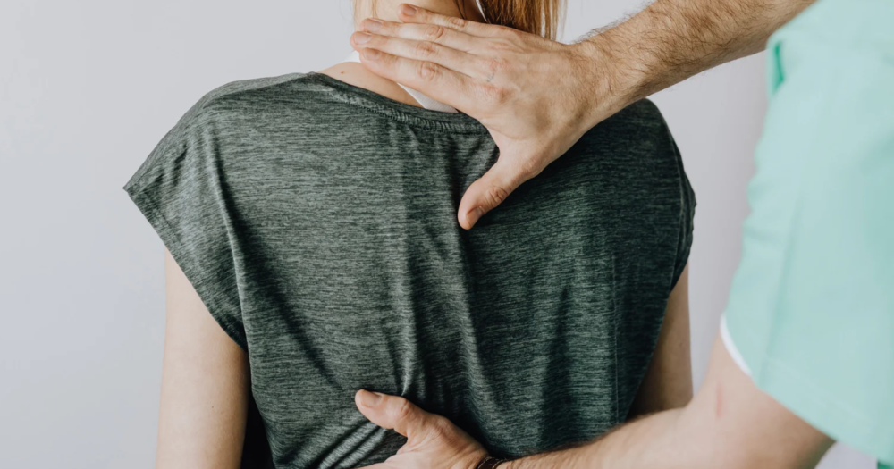 Chiropractor performing a spinal adjustment on a patient's upper back